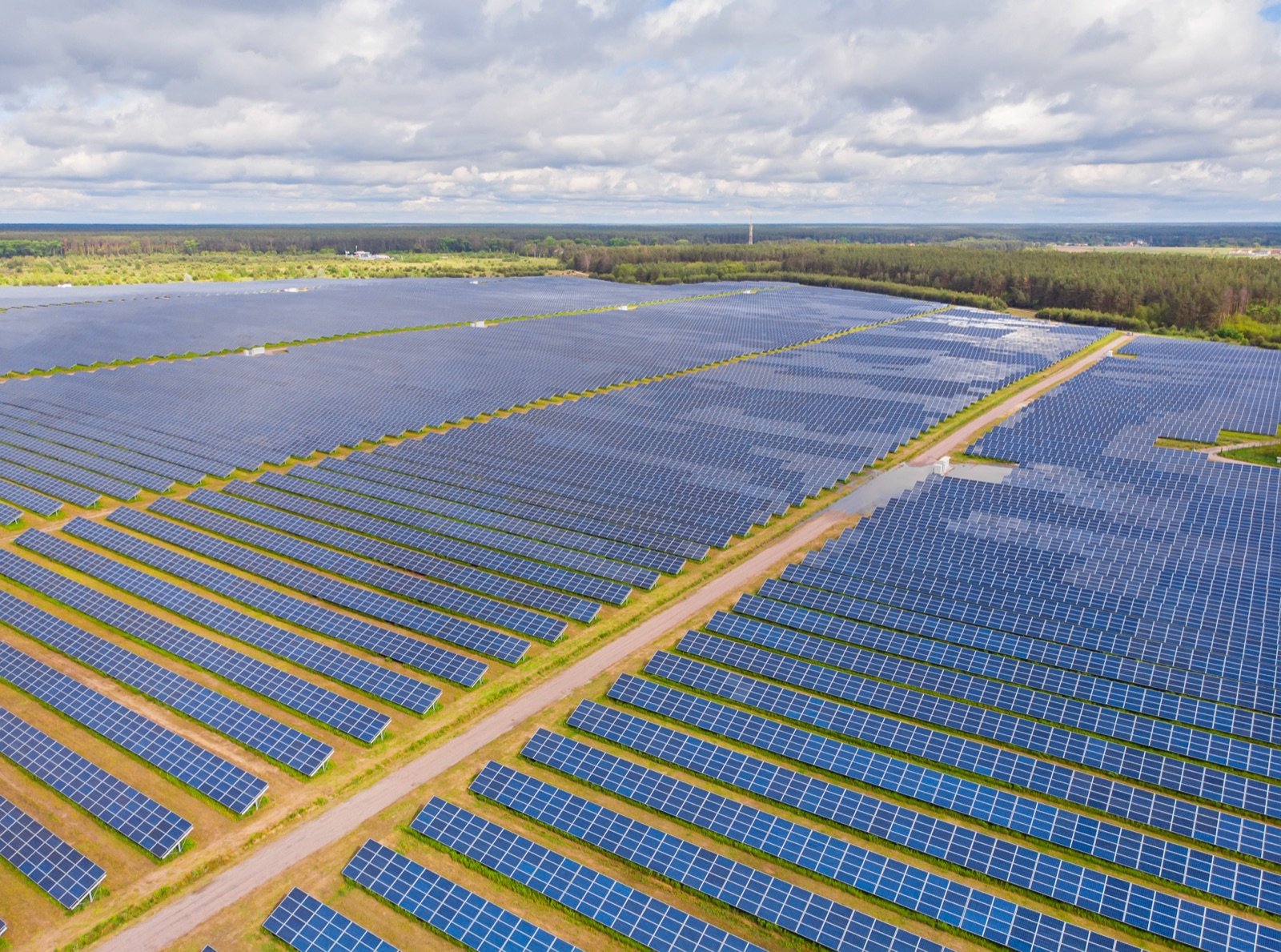 Vista aérea de una planta solar fotovoltaica con filas de paneles sobre terreno abierto